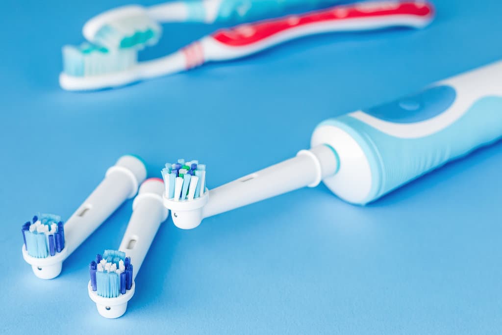 Electric and manual toothbrush on blue background