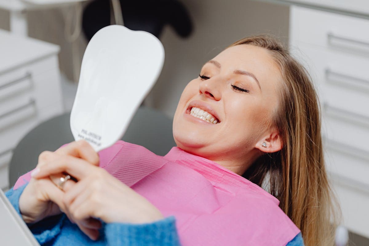 Smiling Woman in Dentist Chair Looking in Mirror.jpg