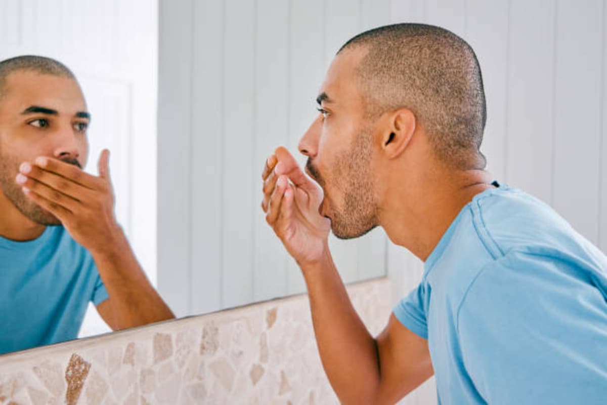 Shot Of A Young Man Smelling His Breath During His Morning.jpg
