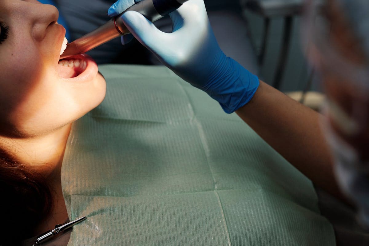 A Person Wearing Blue Latex Gloves Checking Patient's Teeth