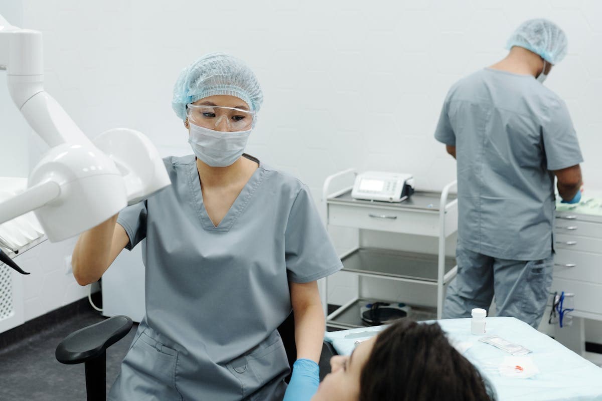 Woman in Gray Scrub Suit Wearing Face Mask Sitting