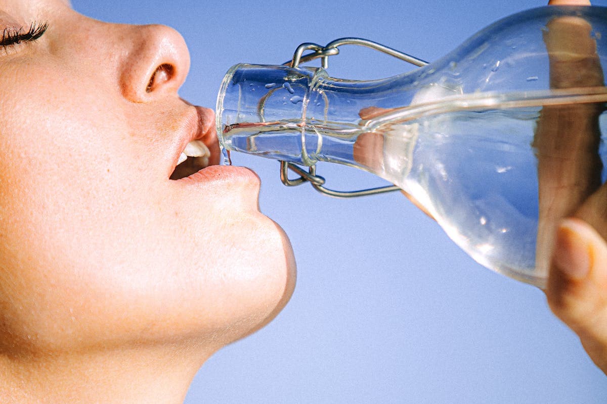Woman Drinking Water From Glass Bottle