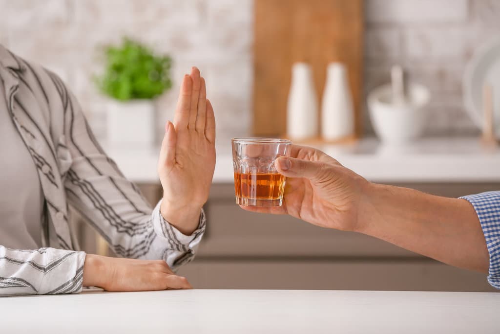 Woman refusing to drink whiskey at home. Concept of alcoholism