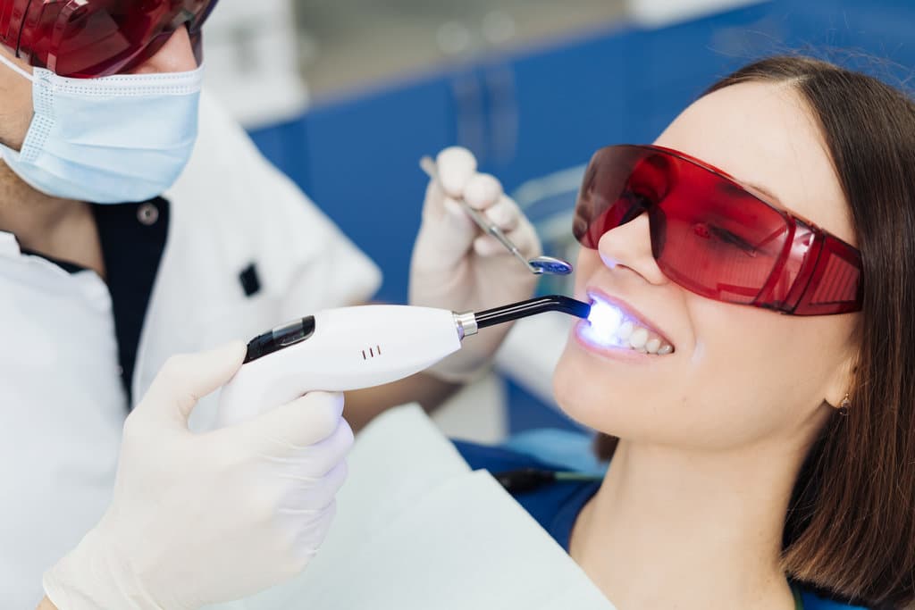 Close-up portrait of a female patient visiting dentist for teeth whitening in clinic